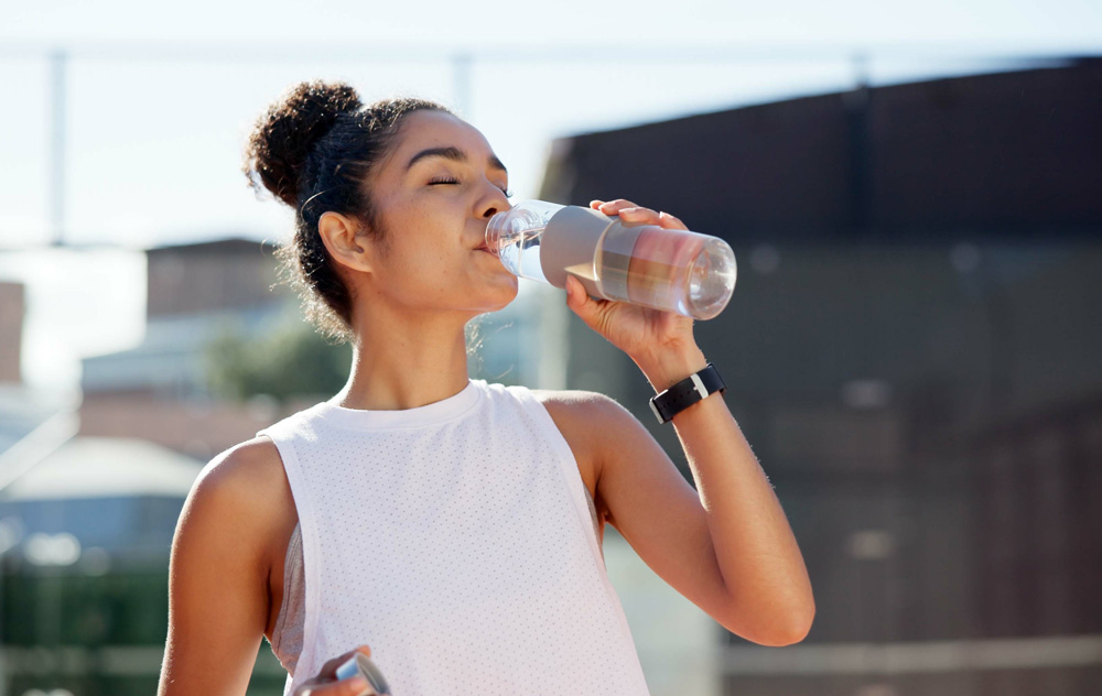 Bild zeigt Frau, welche aus einer Plastikflasche steht. Symbolisiert die Plastikbelastung im Alltag.