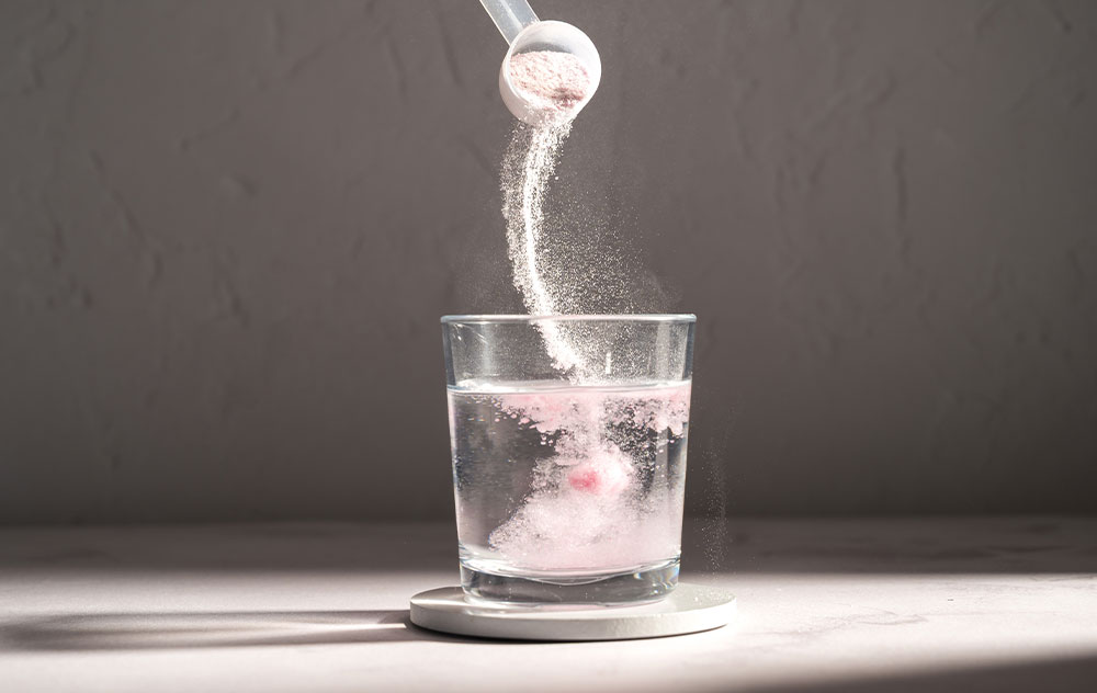 Bild zeigt Kreatin Pulver, welches in Glas Wasser gegeben wird