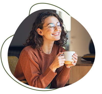 Bild zeigt glückliche Frau, welche eine Tasse mit moon magic latte Pulver trinkt